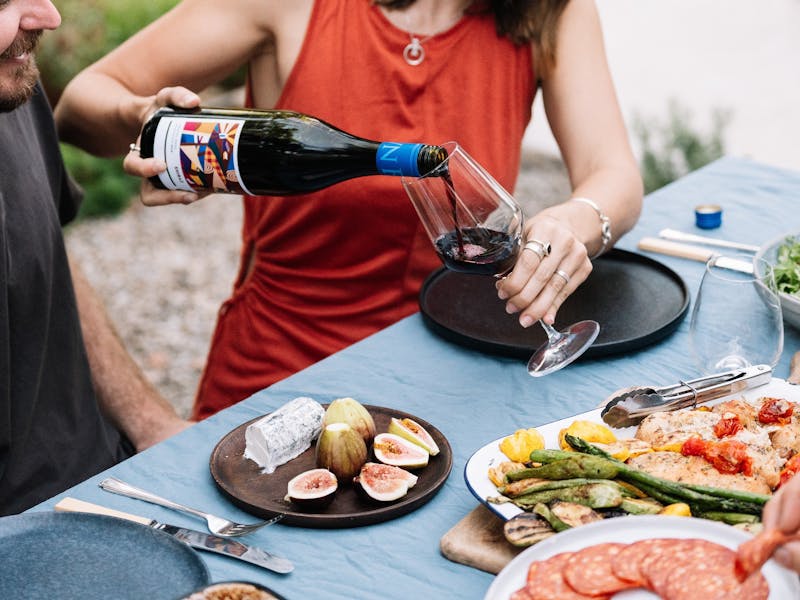 Girl pouring a glass of Origins Series Shiraz on an outdoor table set with food