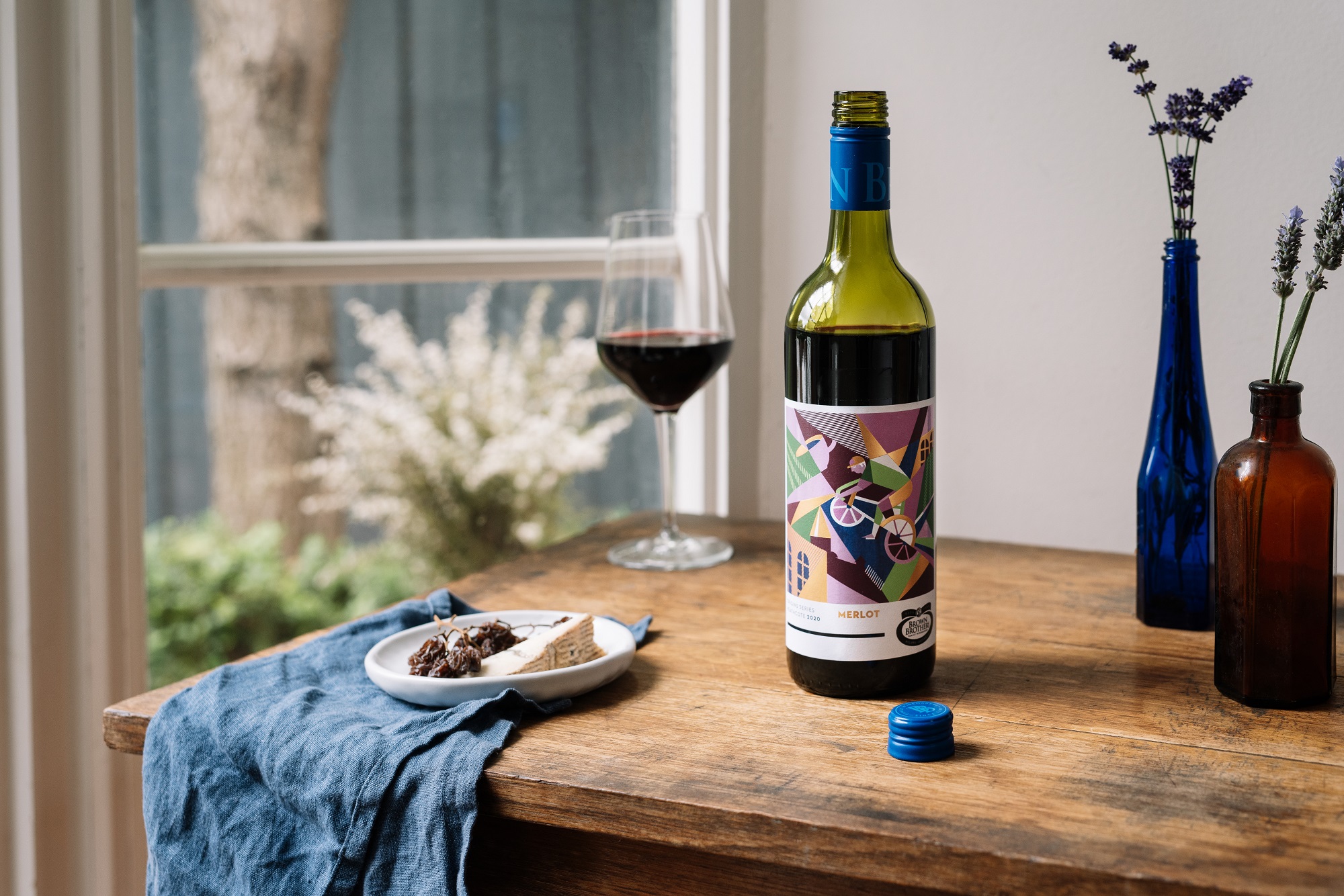 bottle of Origin Series Merlot on a wooden table by the window