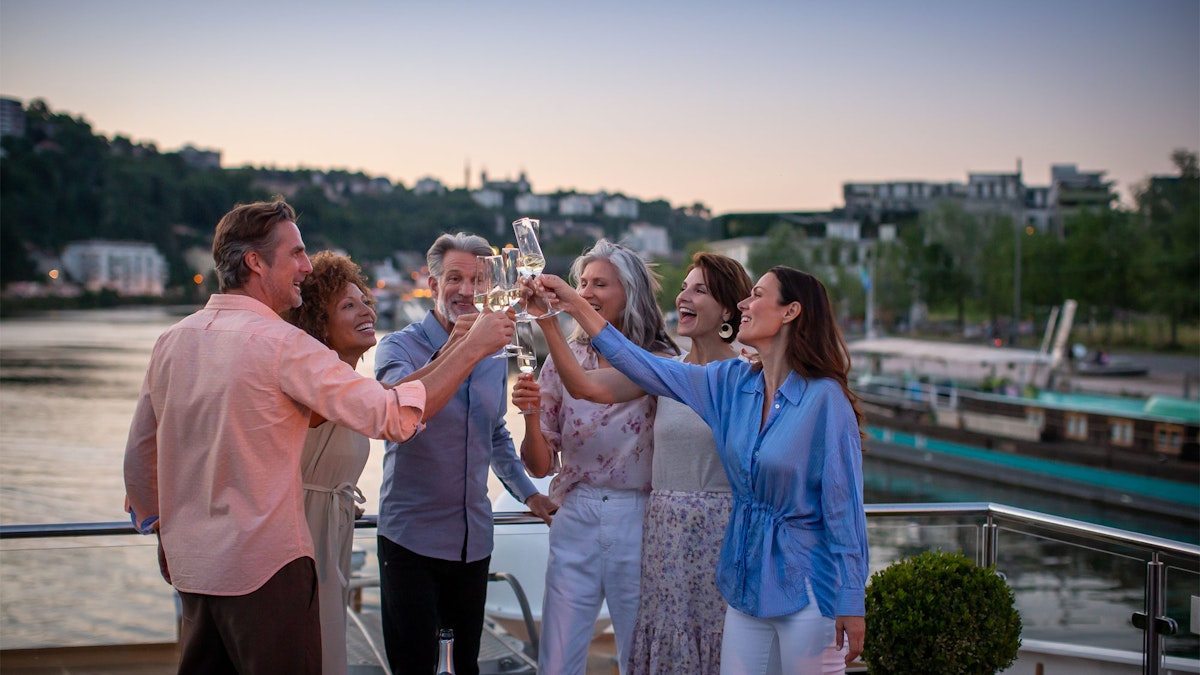 Group of friends celebrating with glasses of sparkling on board a cruise boat 