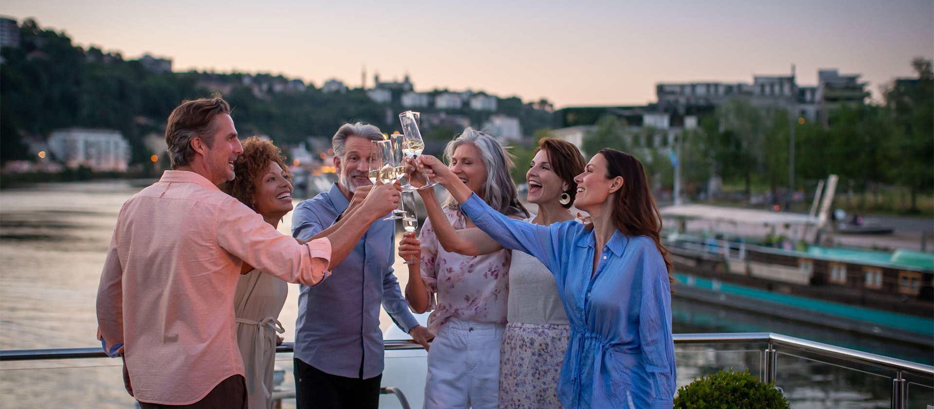 Group of friends celebrating with glasses of sparkling on board a cruise boat 