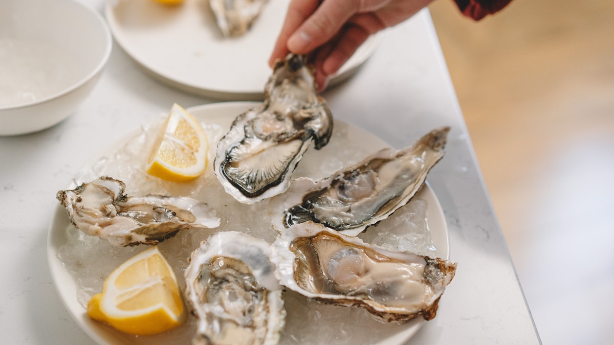 A plate of oysters on ice with fresh lemon