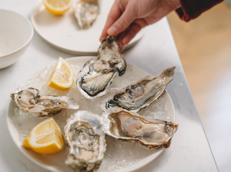 A plate of oysters on ice with fresh lemon