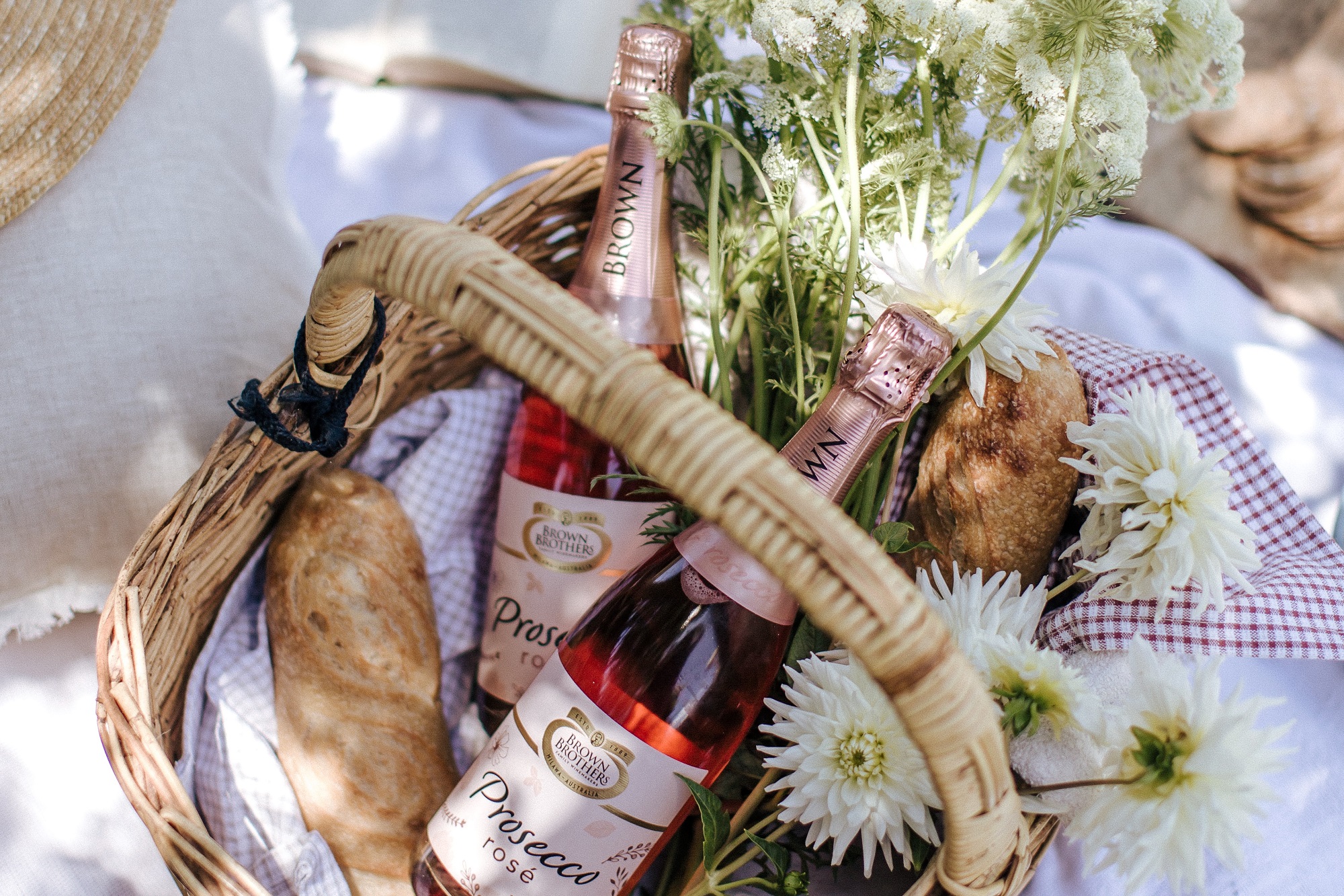 two bottles of prosecco rose NV in a basket with baguette and fresh flowers