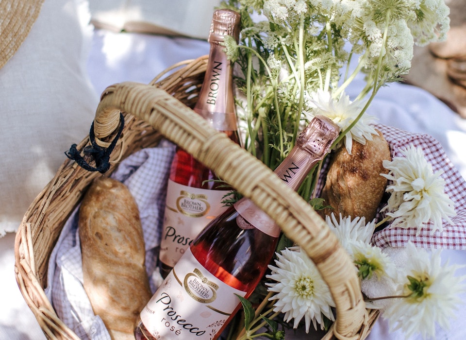 two bottles of prosecco rose NV in a basket with baguette and fresh flowers