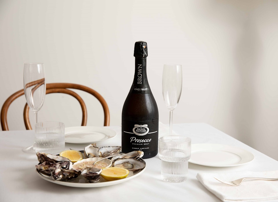 bottle of prosecco premium brut on a table set with oysters