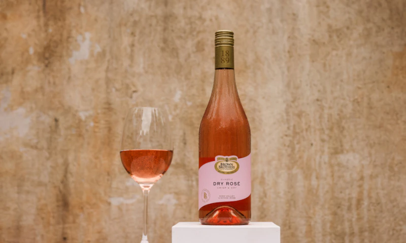 A bottle of Brown Brothers Classic Dry Rose with a glass of wine with rose in it.