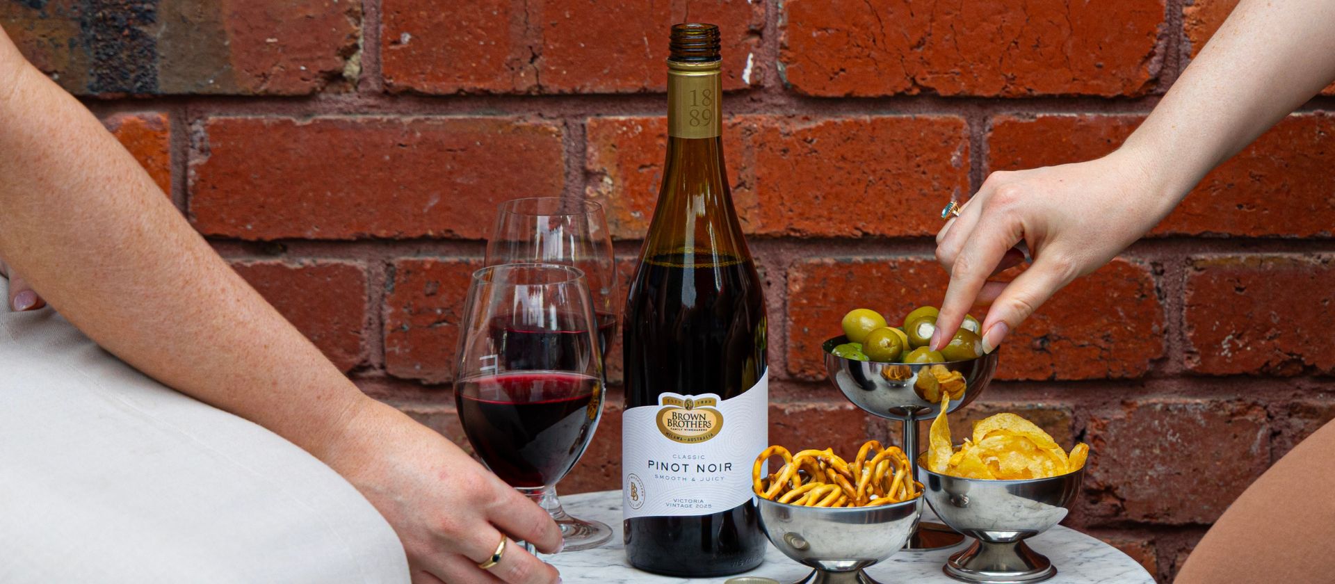 An open wine bottle on a table with nibbles