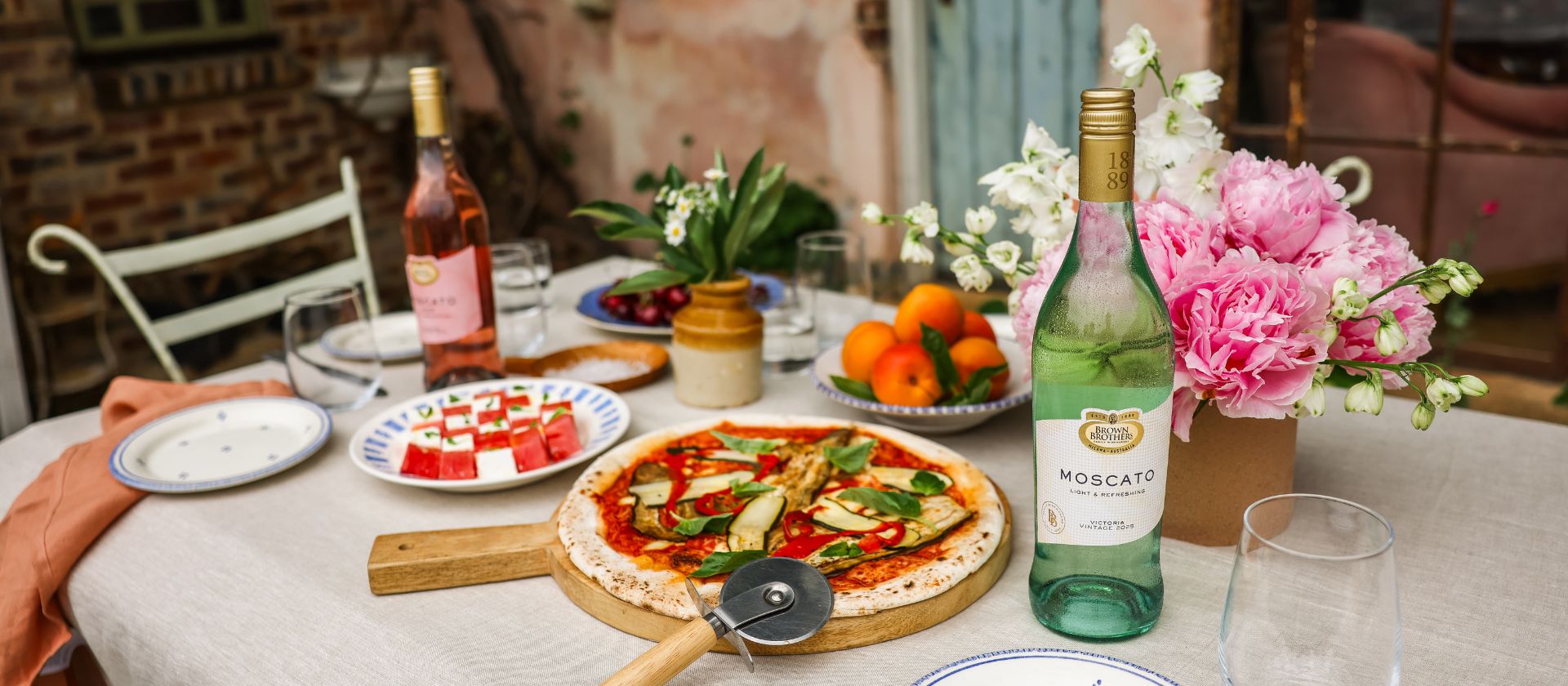 A table with pizza and bottles of Brown Brothers Moscato