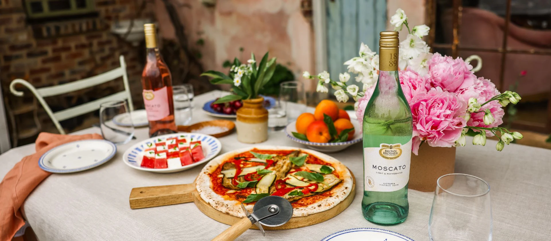 A table with pizza and bottles of Brown Brothers Moscato