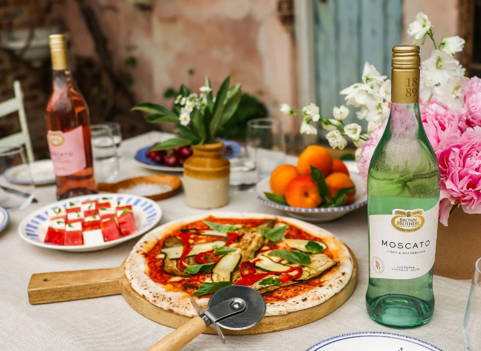 A table with pizza and bottles of Brown Brothers Moscato