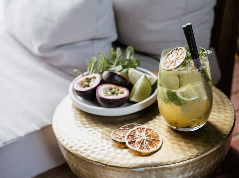 Passionfruit Mojito in a glass next to a bowl of fresh passionfruit