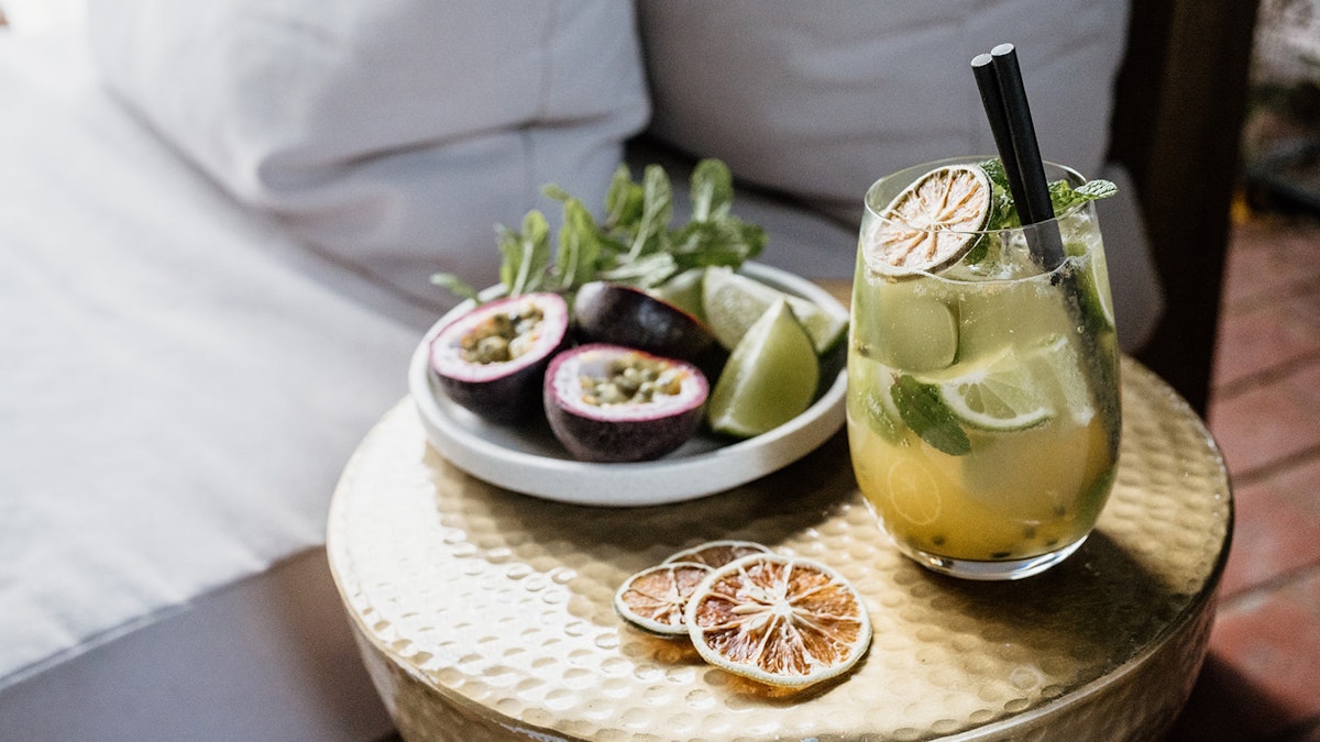 Passionfruit Mojito in a glass next to a bowl of fresh passionfruit