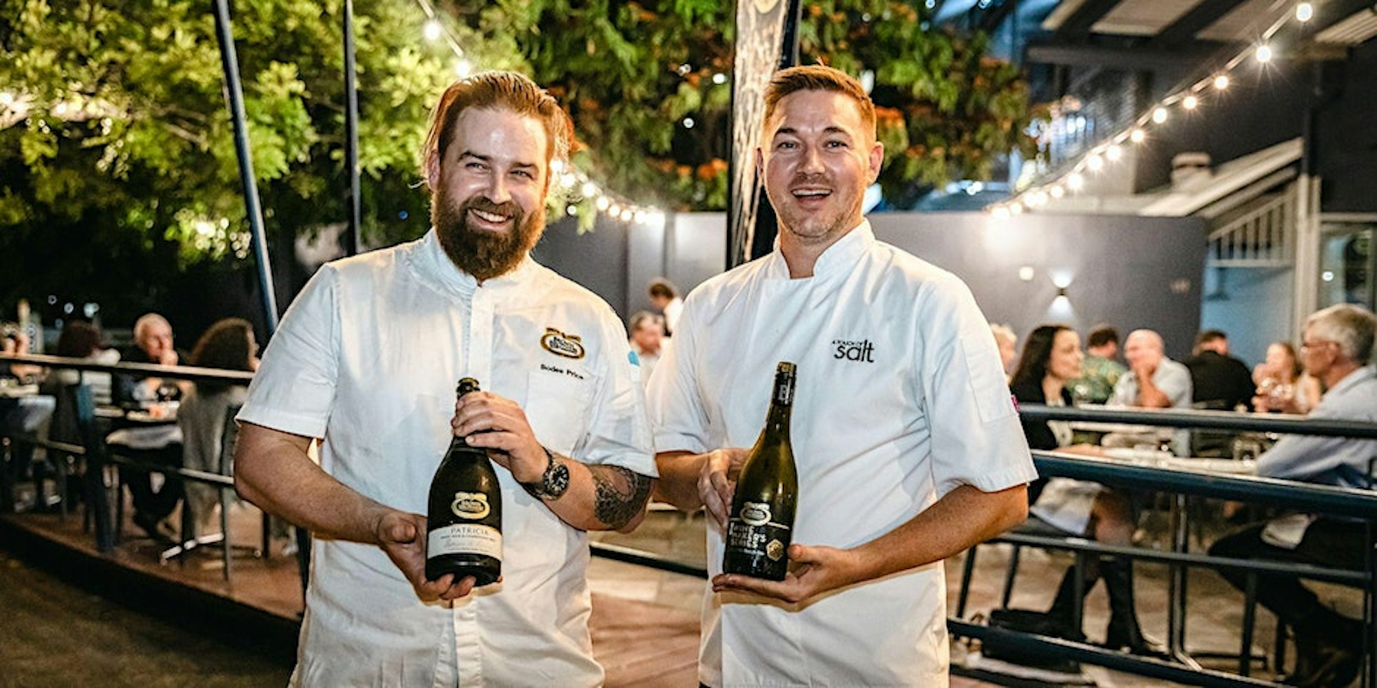 Head Chef Bodee Price with A Touch of Salt Head Chef Michael Brine, each holding a bottle of Brown Brothers wines