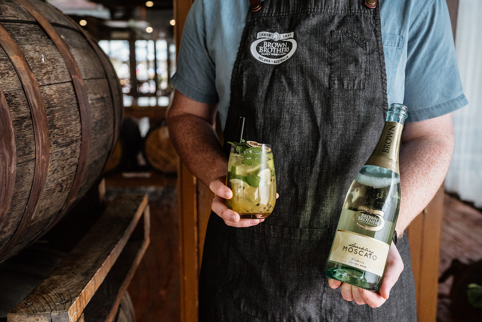 Brown Brothers team member holding a bottle of sparkling moscato and a cocktail