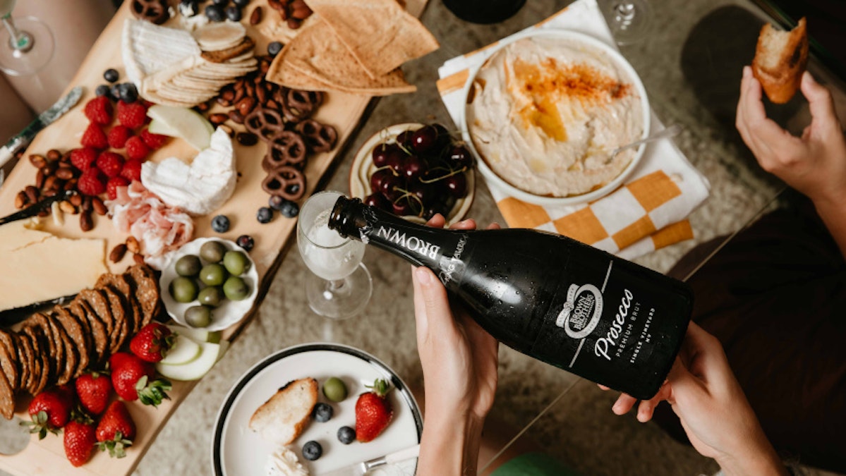 Bottle of Premium Proseccu Brut being poured over a grazing board