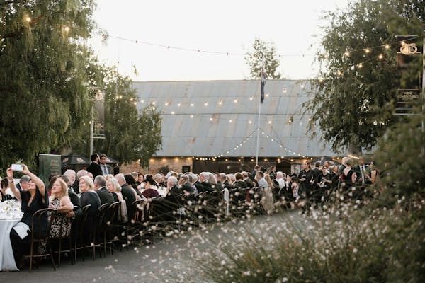 Long table of guests seated outside in the grounds at Brown Brothers Winery