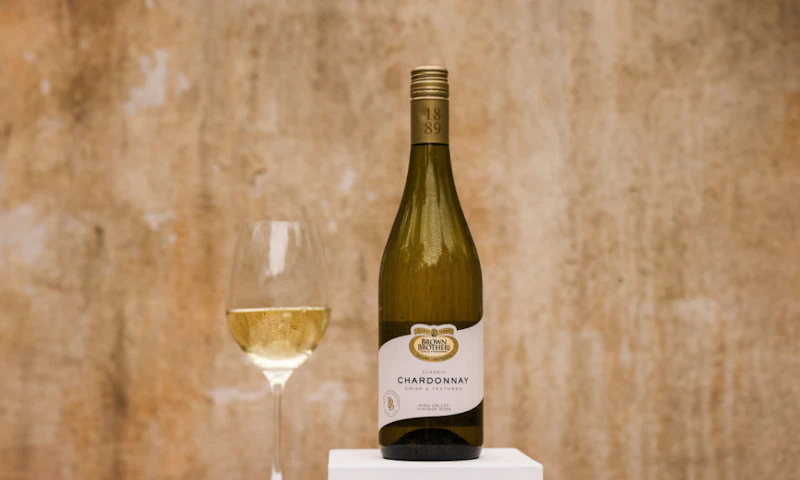 A bottle of Brown Brothers Classic Chardonnay with a wine glass