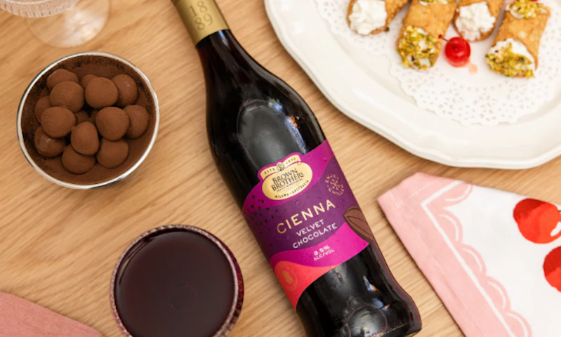 A flatlay of Brown Brothers Cienna Velvet with chocolates and cannoli
