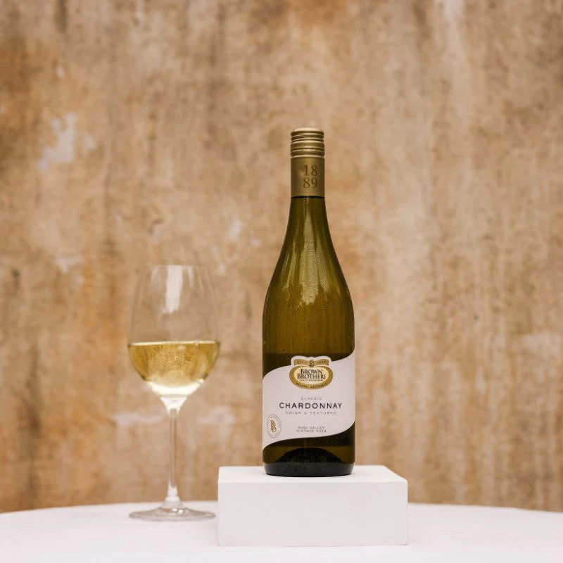 A bottle of Brown Brothers Classic Chardonnay with a glass of wine