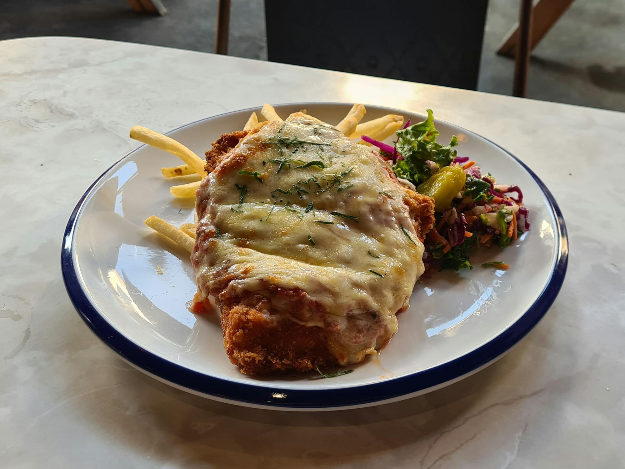 Slab of crumbed, fried chicken, covered in marinara sauce and melted cheese
