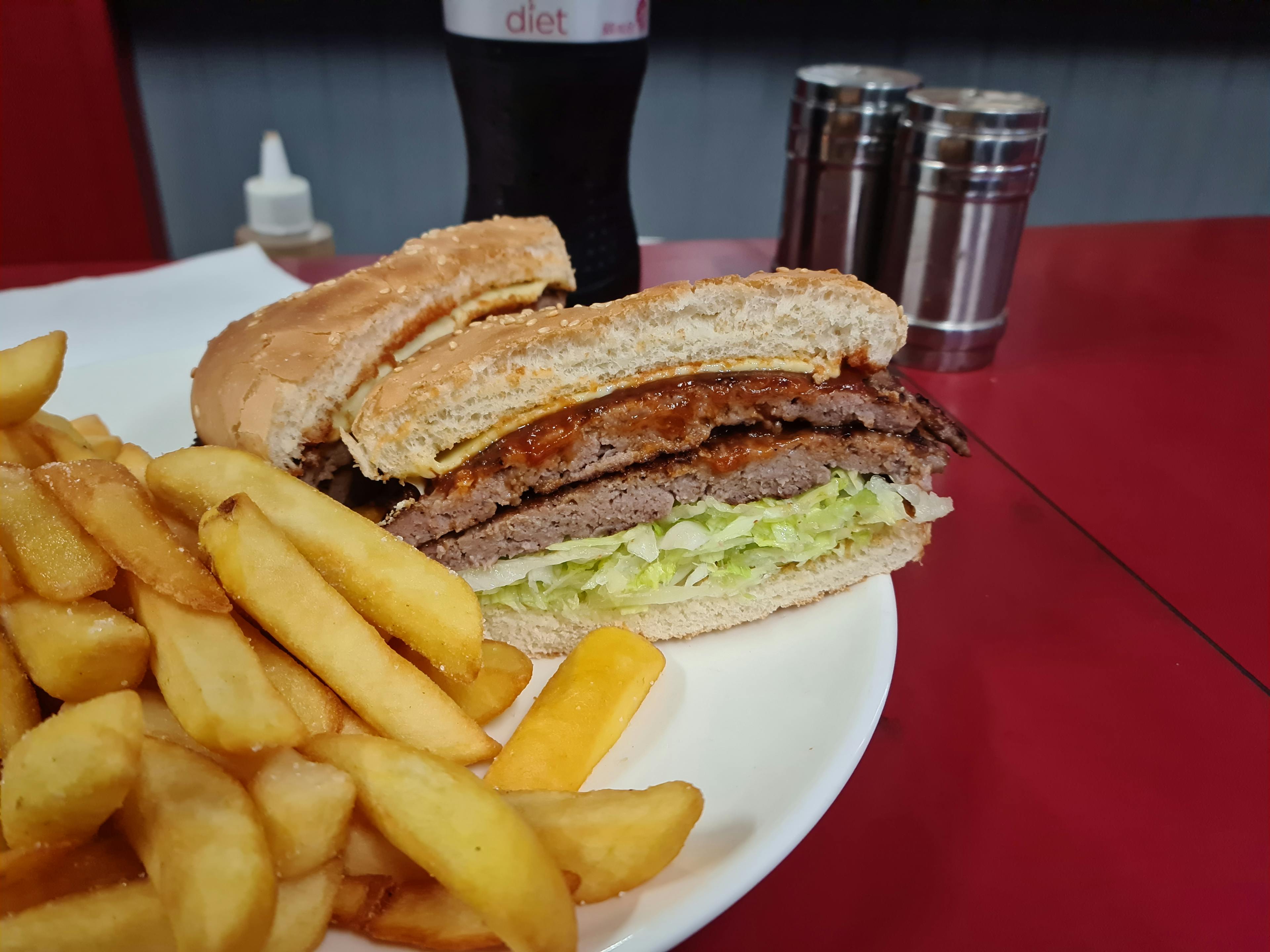 Cross section of a double cheeseburger showing thick patties behind a mound of steak-cut fries.