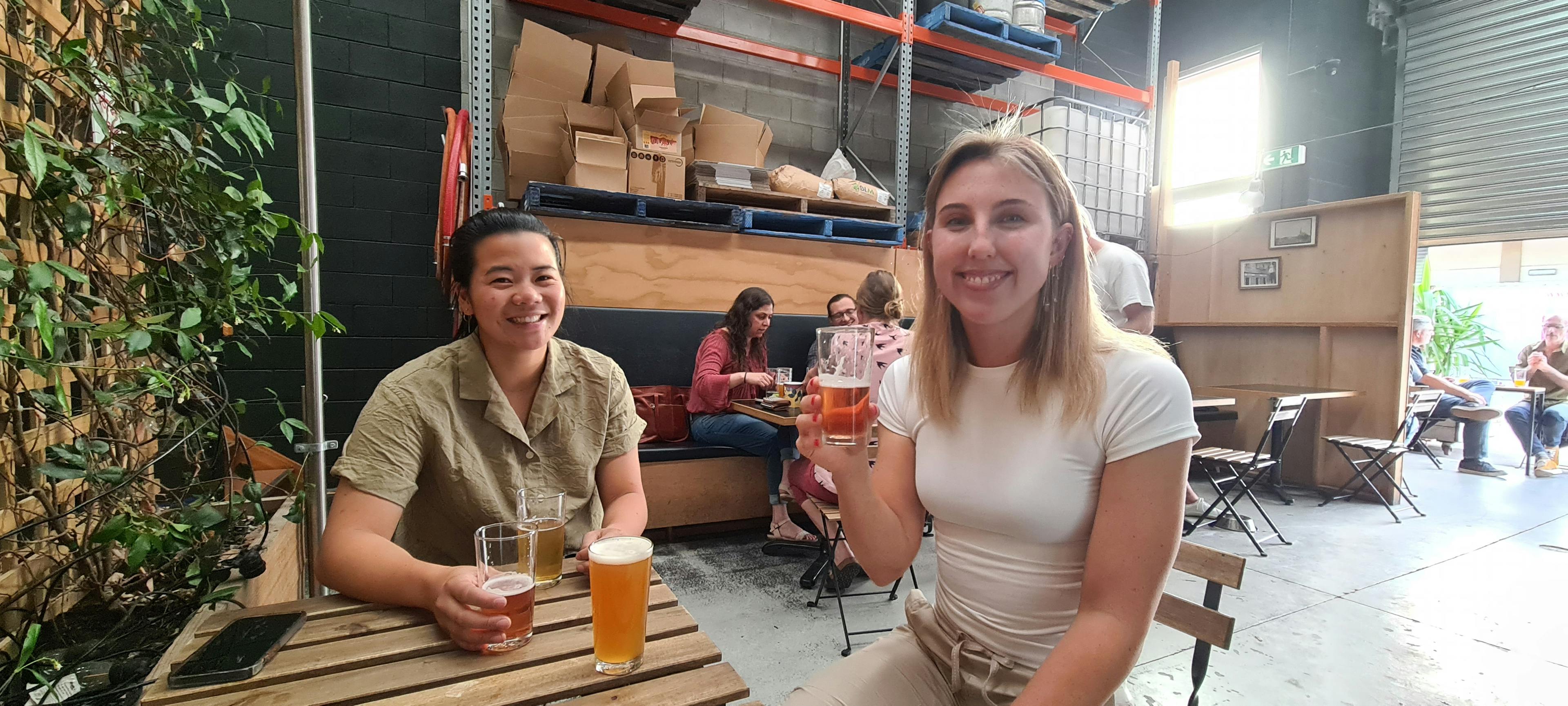 Caroline and Jess smiling at the camera while drinking beer