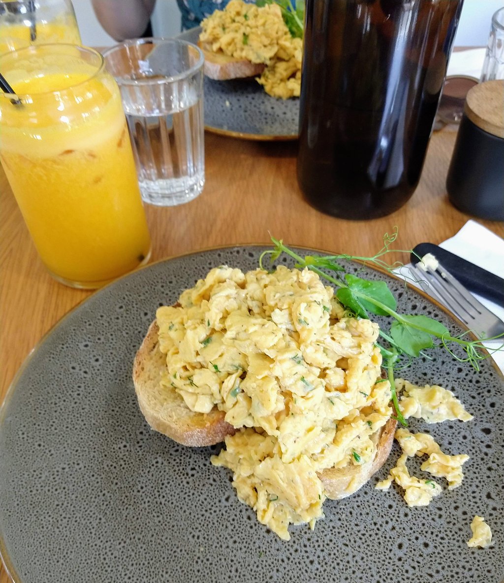 Scrambled eggs on a slice of toasted sourdough with orange juice in the background