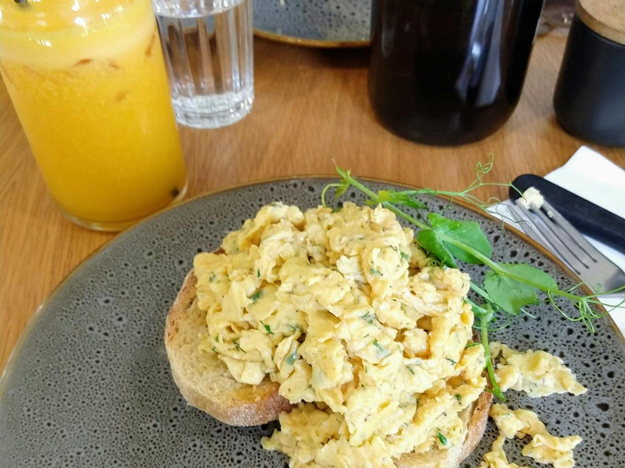 Scrambled eggs on a slice of toasted sourdough with orange juice in the background