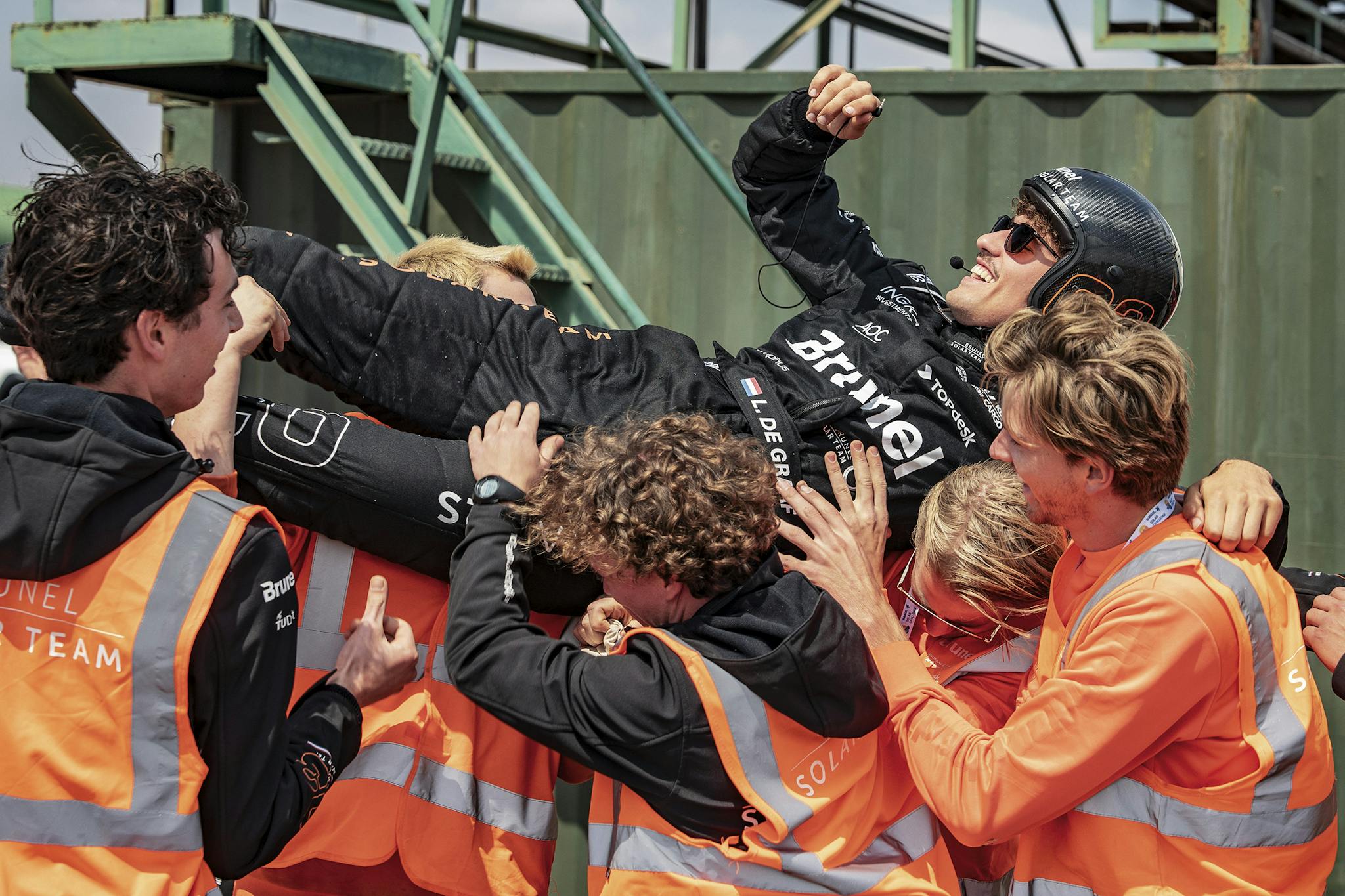 Coureur wordt opgetild door het team na het behalen van de eerste plek bij de kwalificatie