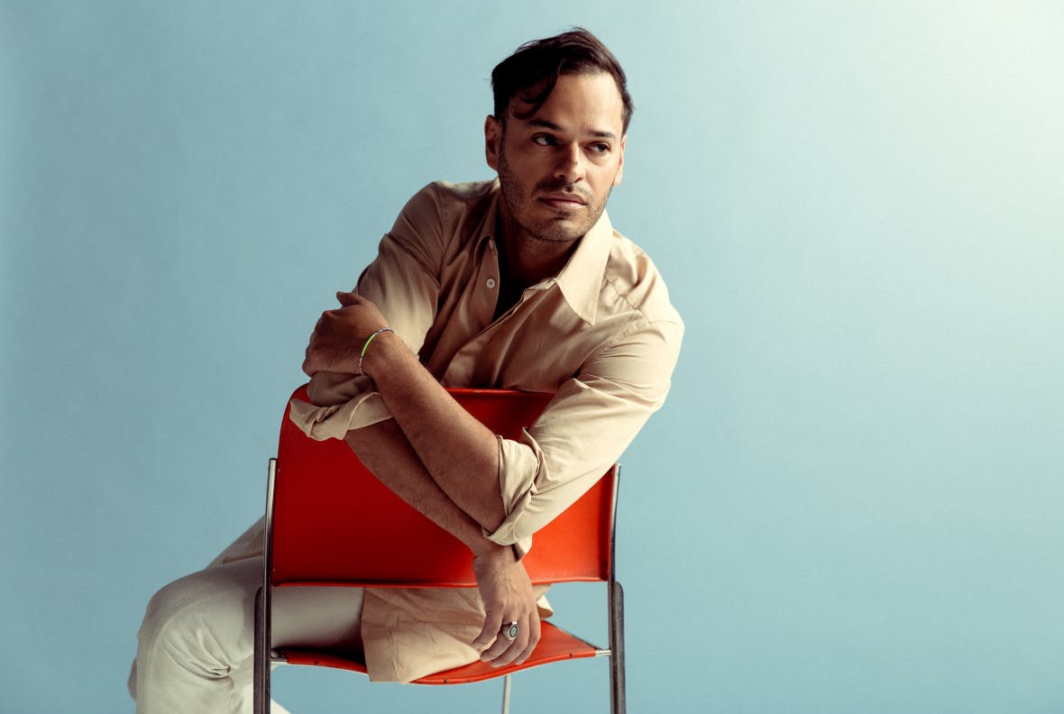 Bryan Senti sitting in an orange chair looking off camera