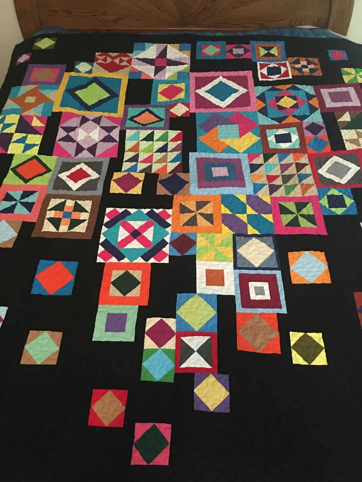 Colorful squares with various patterns on a black quilt