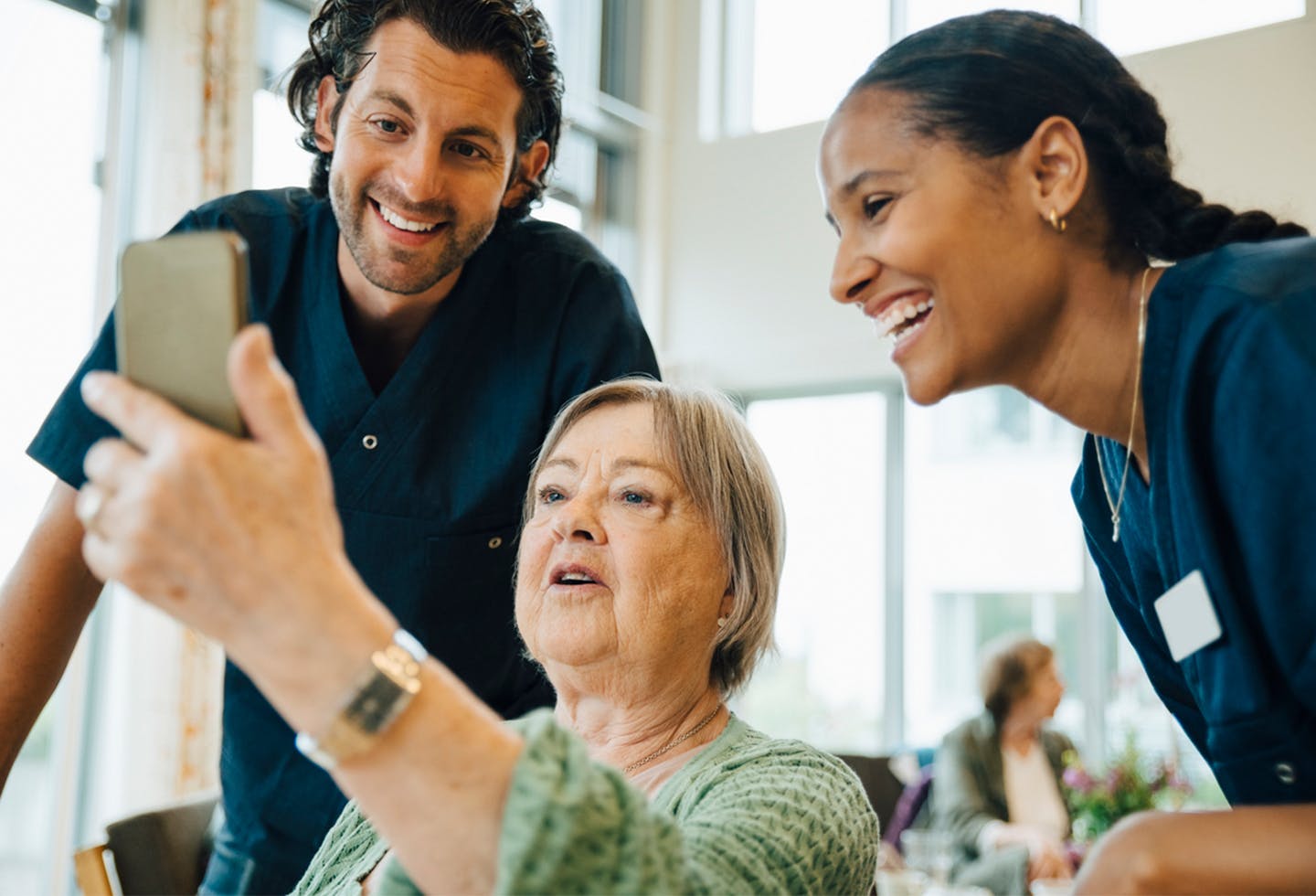 Elderly patient showing two medical assistants her smart phone screen