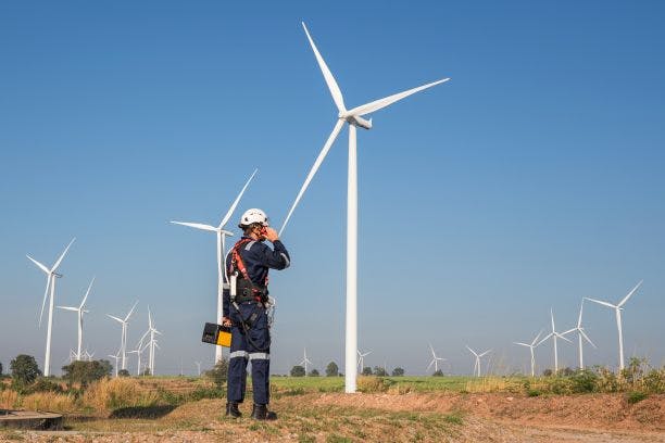 Homme devant un champs d'éolienne