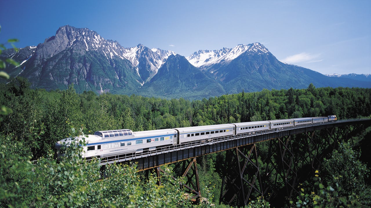 A passenger train crossing a bridge in the mountains
