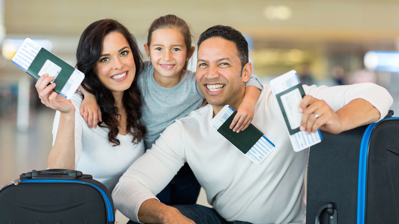 happy family holding boarding pass and passport at airport