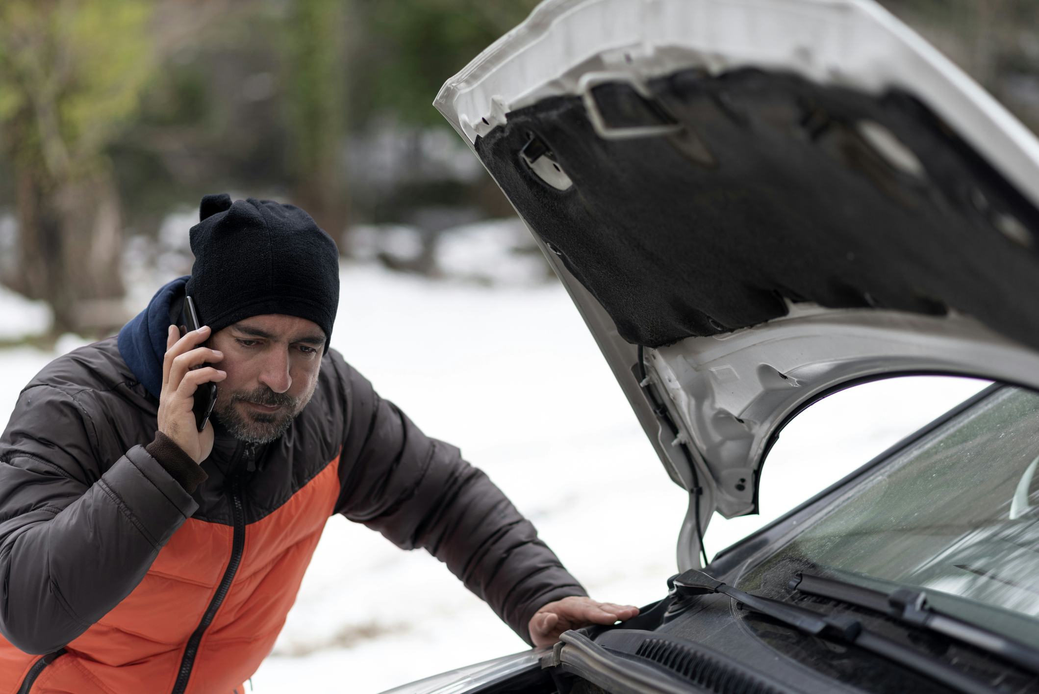 a man calling for help for a car breakdown on a snowy winter day