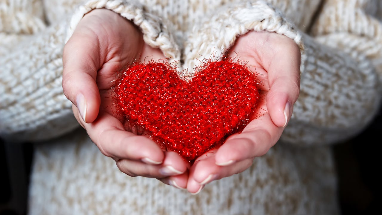 Woman's hands holding a red knitted heart
