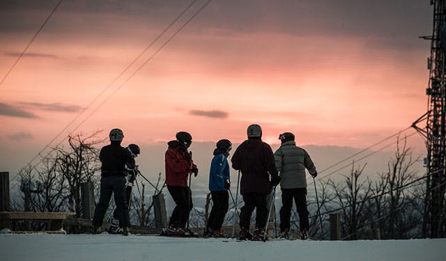 A group of skiers at the top of the ski hill