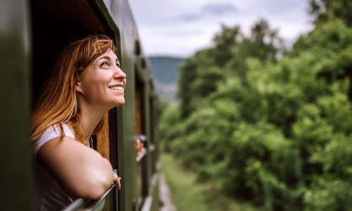 Young smiling woman standing out of the train window