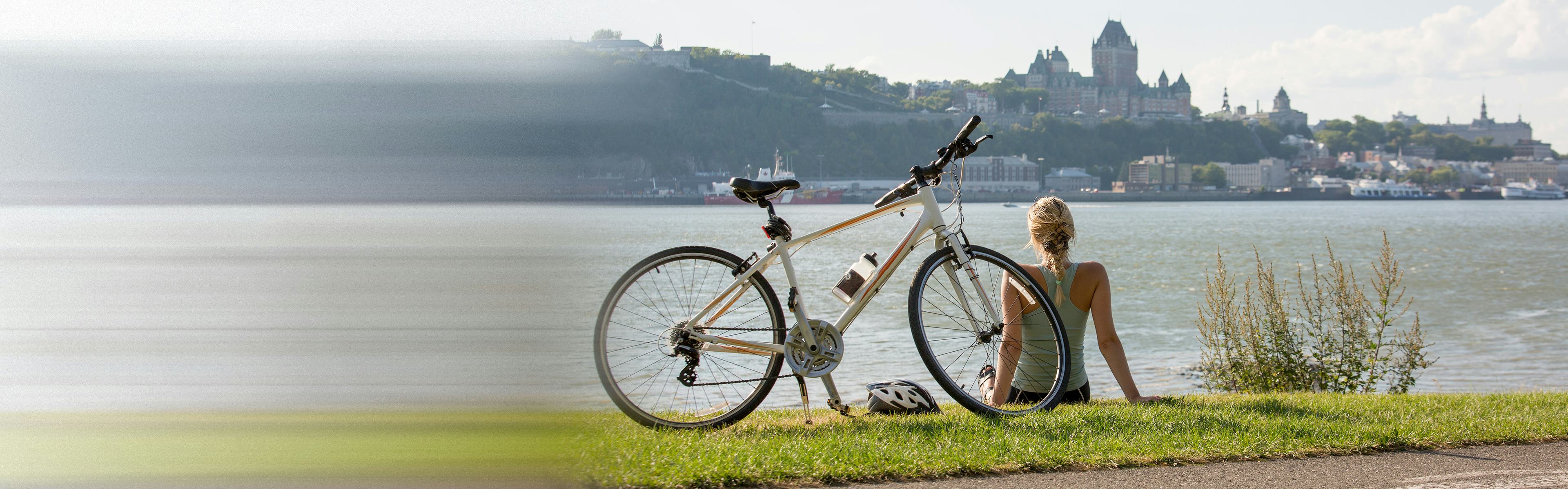 Woman sitting along river bank next to her bike
