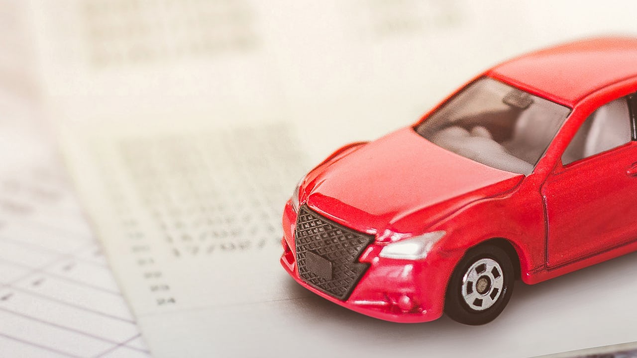 A red toy car on top of insurance paperwork.