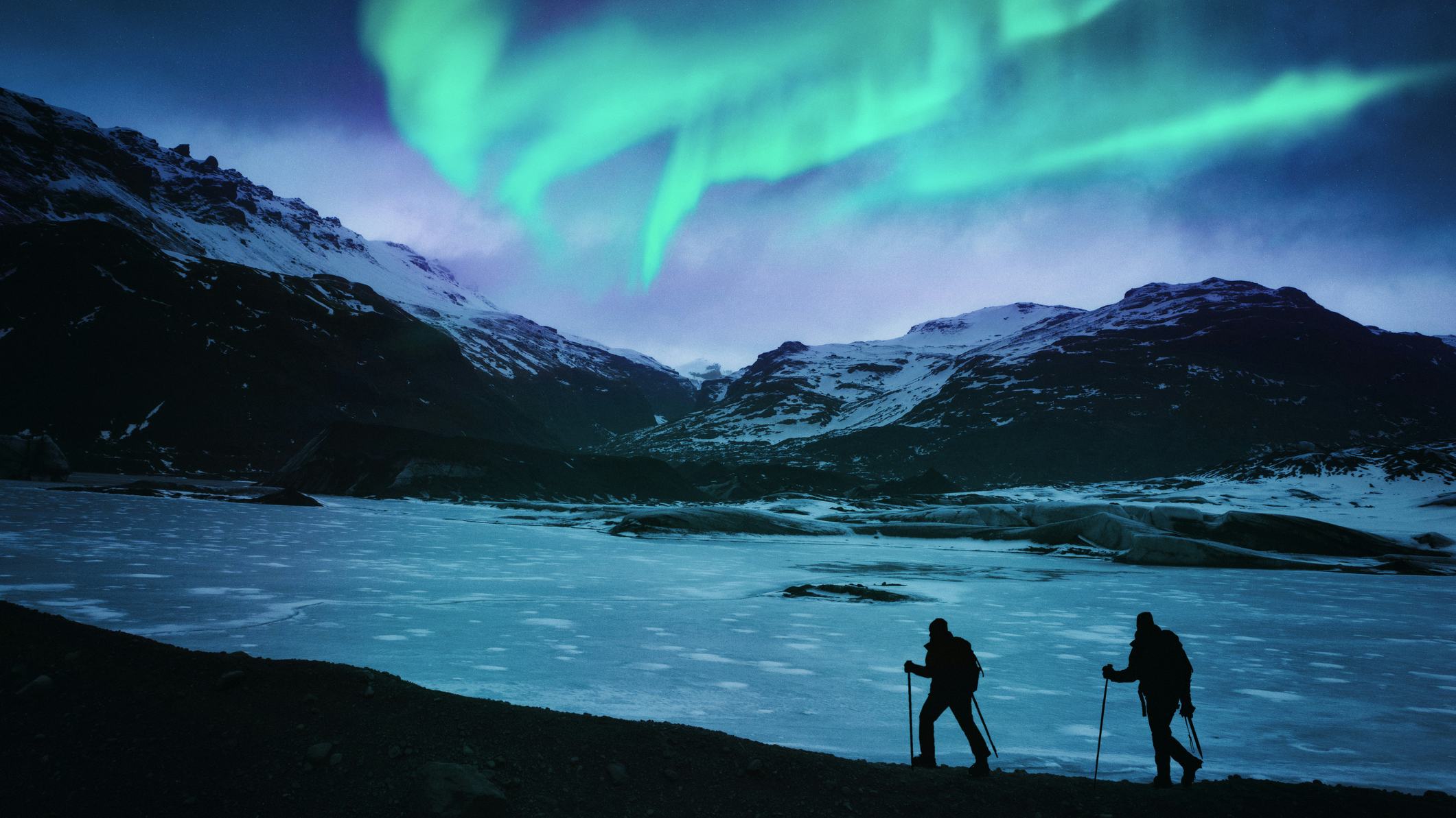 Two hikers in Iceland with the northern lights