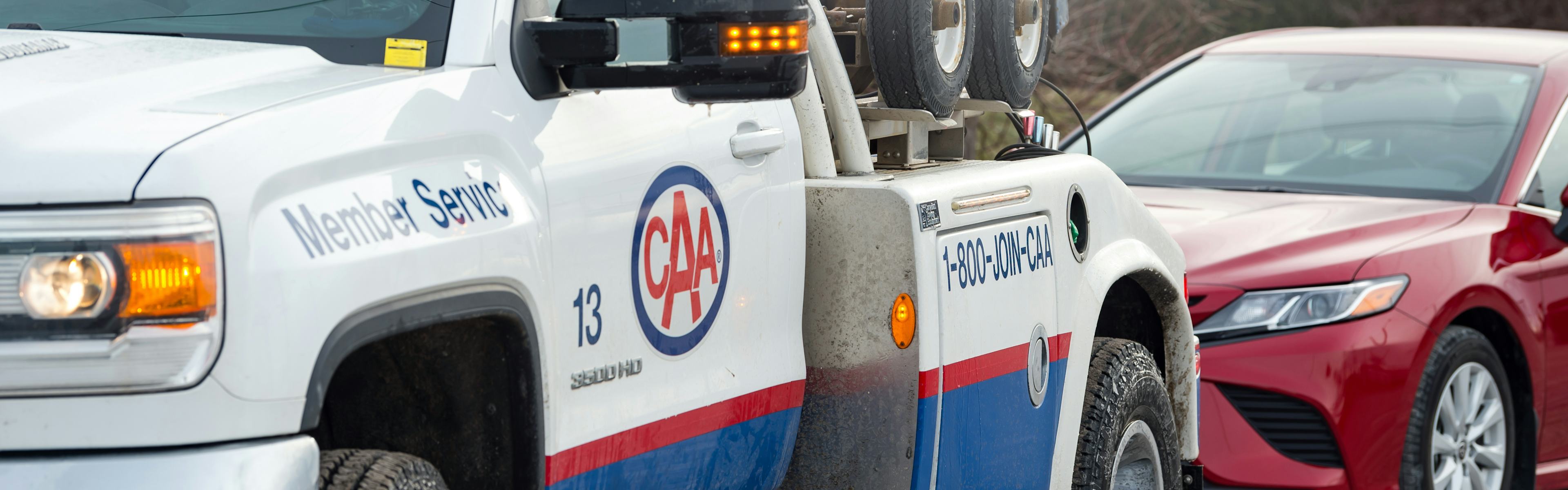 A CAA tow truck providing roadside assistance to a red car. CAA leaves your manufacturers roadside assistance plan in the dust (including kia roadside assistance, mazda roadside assistance, nissan roadside assistance