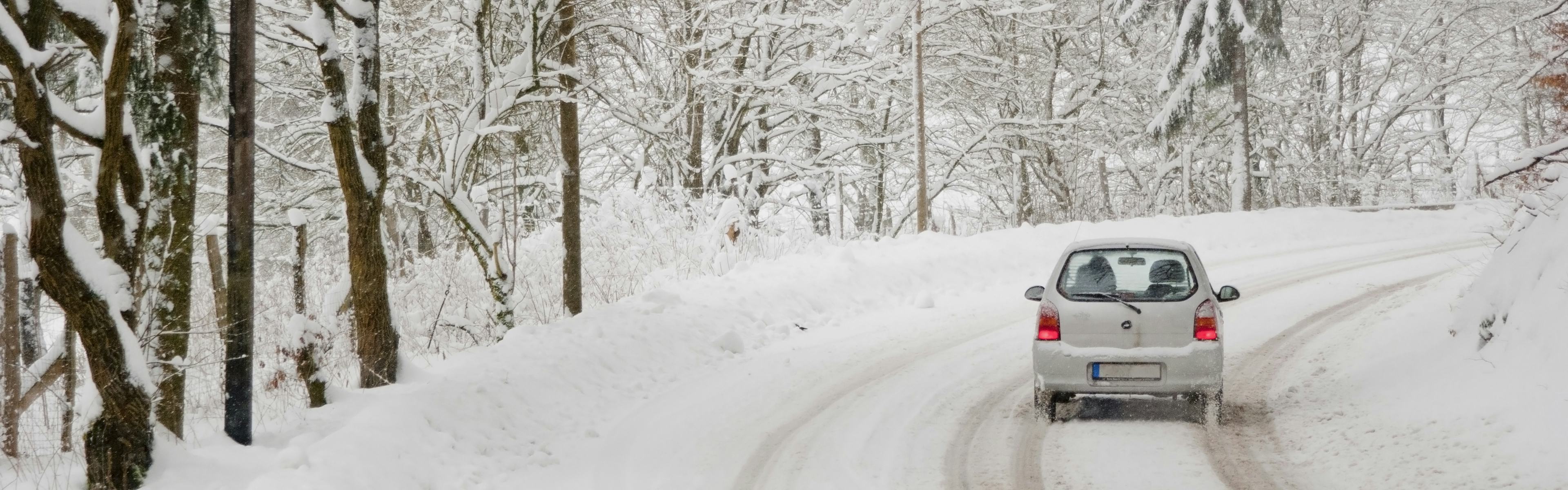 car driving on a winter road in forest. Winter driving can be challenging, luckily CAA is here to help.