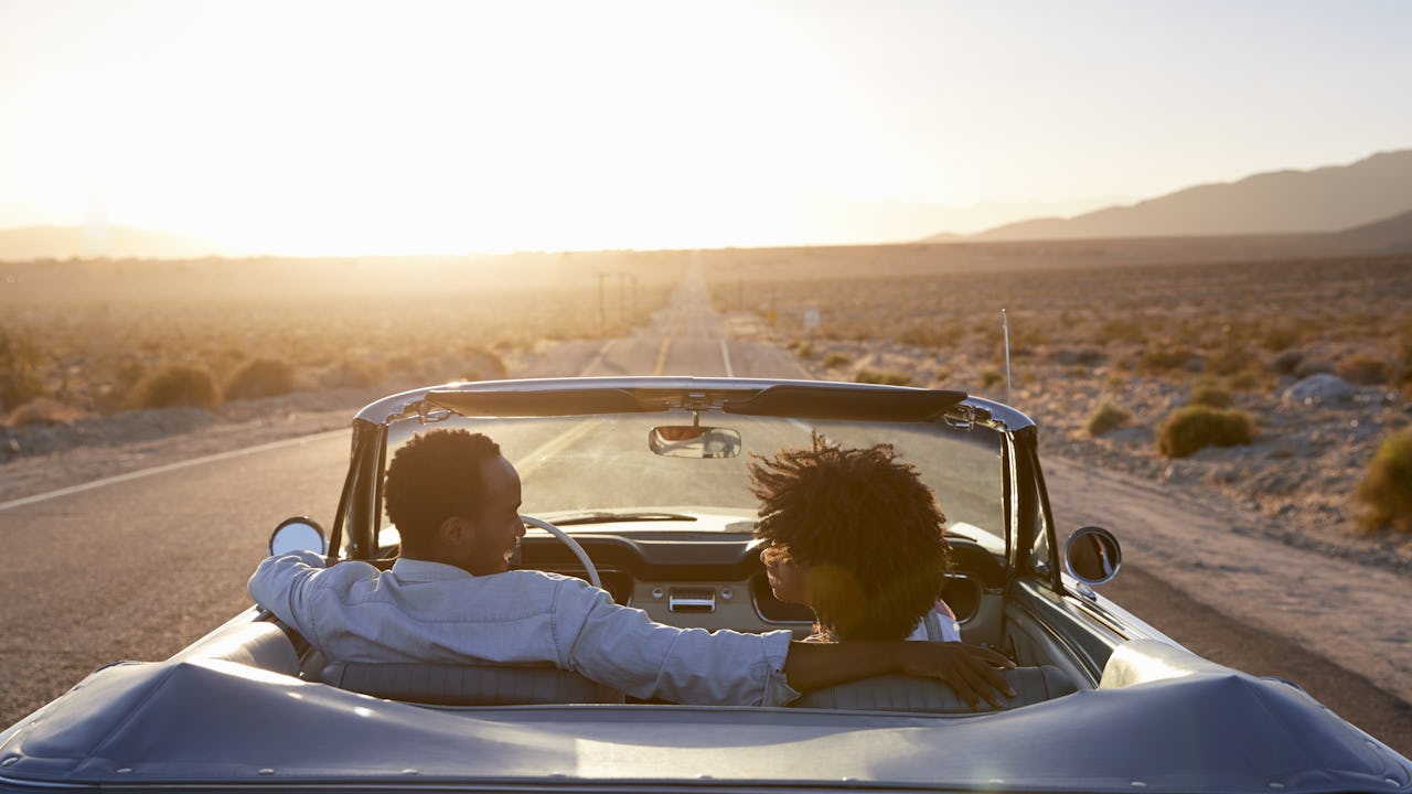Rear view of couple on road trip in convertible at sunset