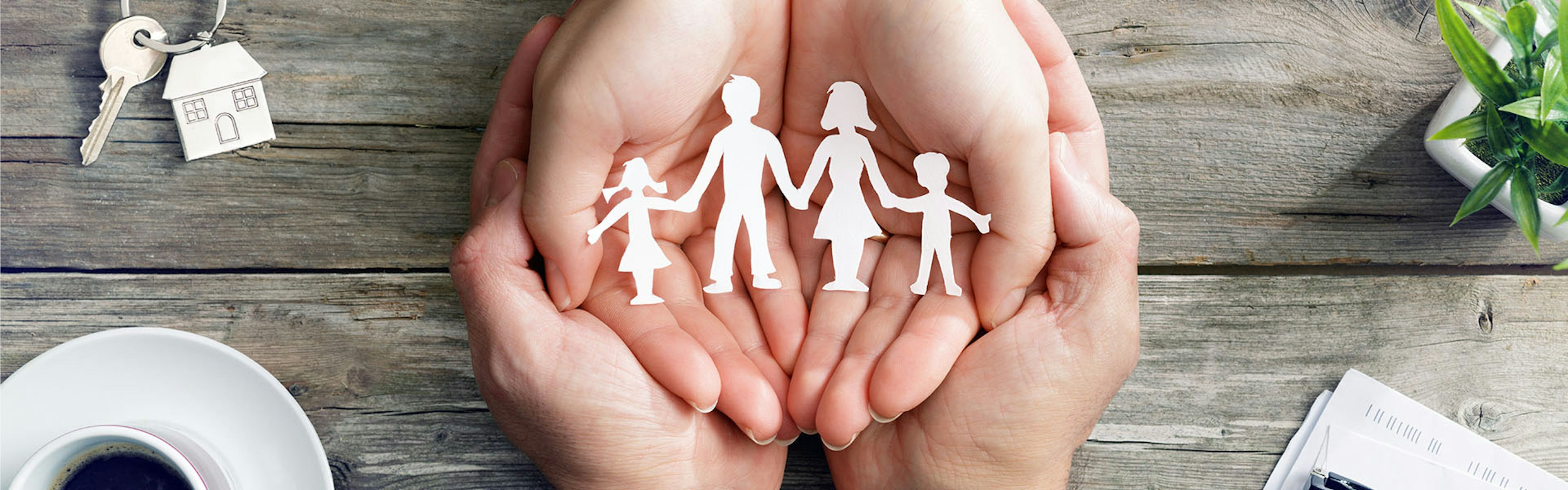 Hands holding a paper cutout of a family.