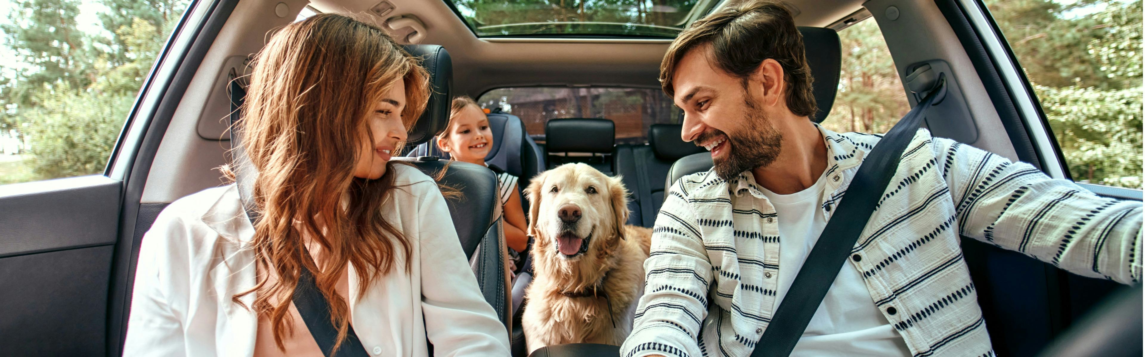 family in a car with their dog