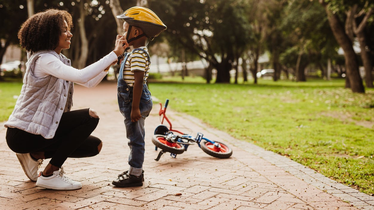 Mother and son putting on bike helmet 