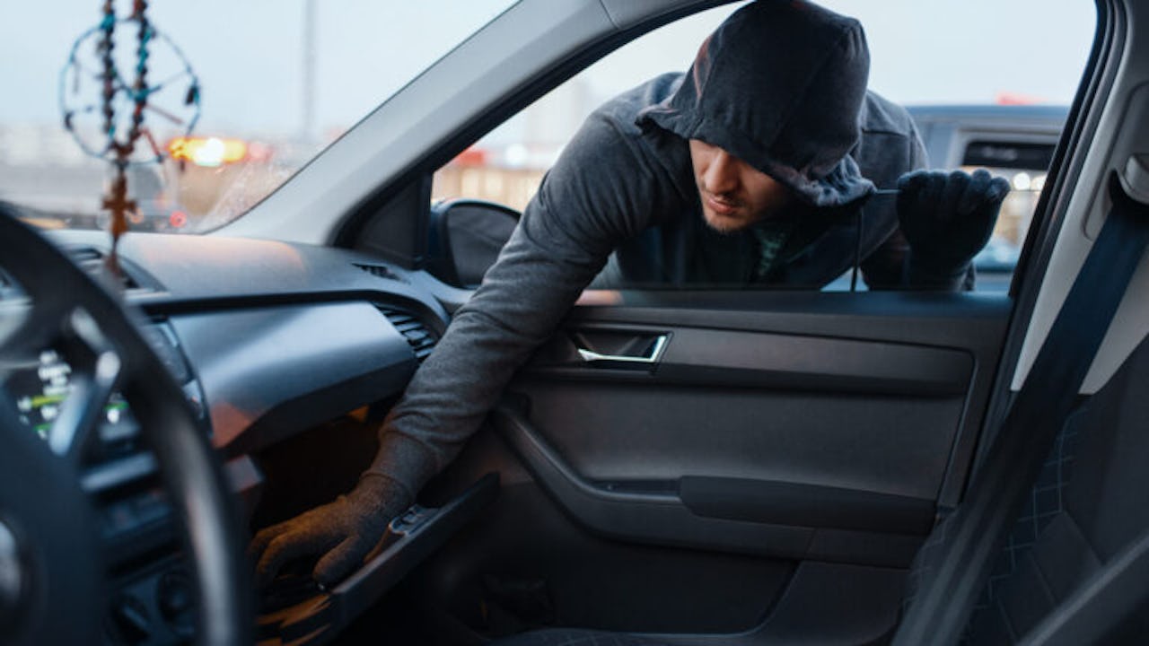 A hooded thief stealing from a glove compartment