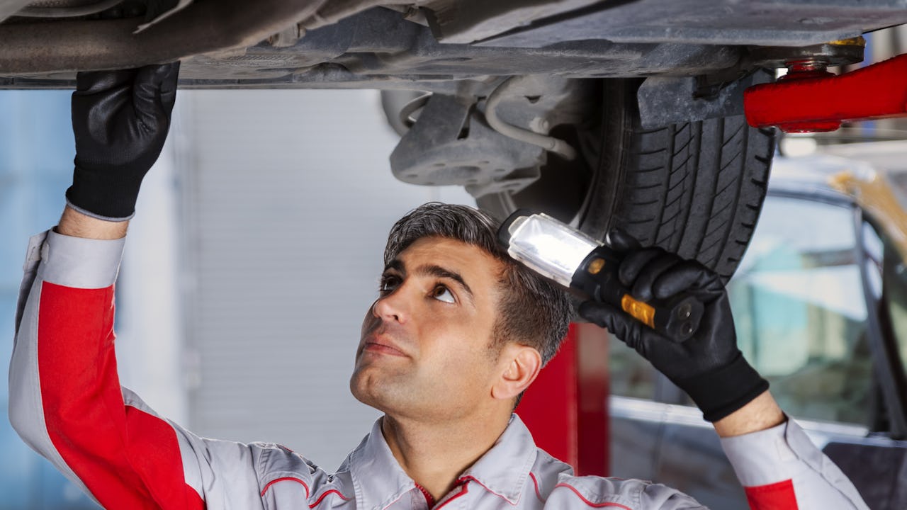 Auto mechanic examining the underneath of a car 
